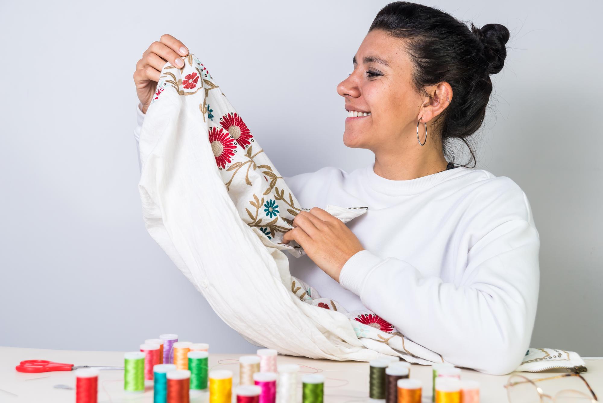 Artist in studio holding embroidered fabric